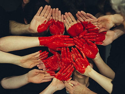 hands formed together with red heart paint