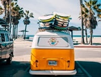 VW van with surf boards by beach