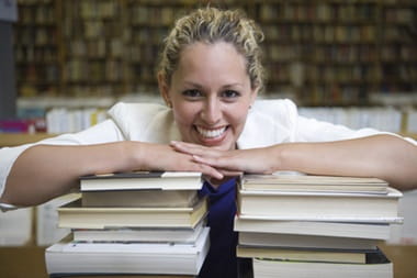 Woman entrepreneur leaning over pile of books