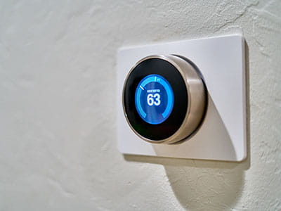 gray Nest thermostat displaying at 63