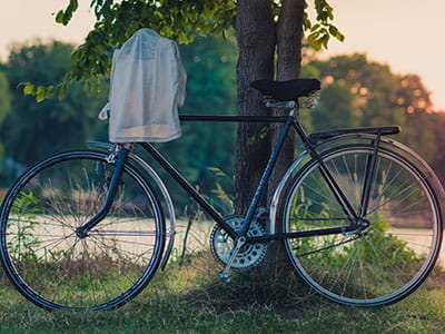 white cloth hanged on bike's handlebar leaned on tree