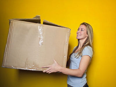 Woman In Grey Shirt Holding Brown Cardboard Box