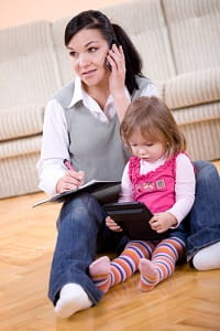 Mother on phone whilst reading to baby daughter