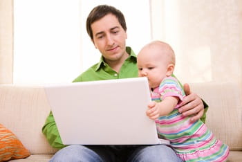 Father & baby looking at laptop screen.
