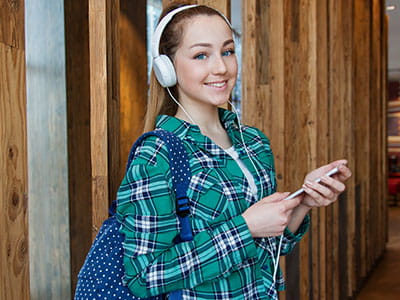 Woman in Teal, White, and Black Plaid Dress Shirt Standing Beside Brown Wall