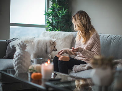 woman sitting on sofa while holding food for dog