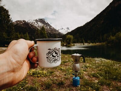 Image of man holding a camping mug for tent camping organisation ideas 