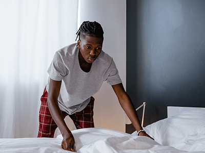 An image of a man making a bed for our printable spring cleaning checklist