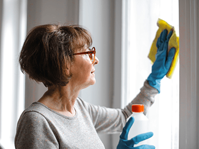 An image of a woman cleaning a window for our printable spring cleaning checklist