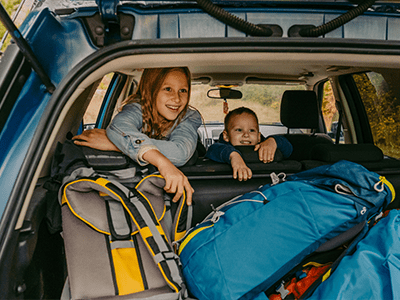 An image of children in a car with overnight bags for our guide on how to pack a car for a road trip