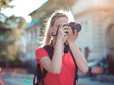 An image of a woman taking a picture in the city for our page on summer hobbies