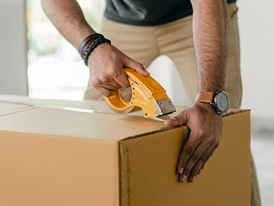 An image of someone sellotaping a cardboard box for our guide to temporary accommodation