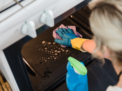 An image of a woman cleaning an oven for our kitchen cleaning checklist